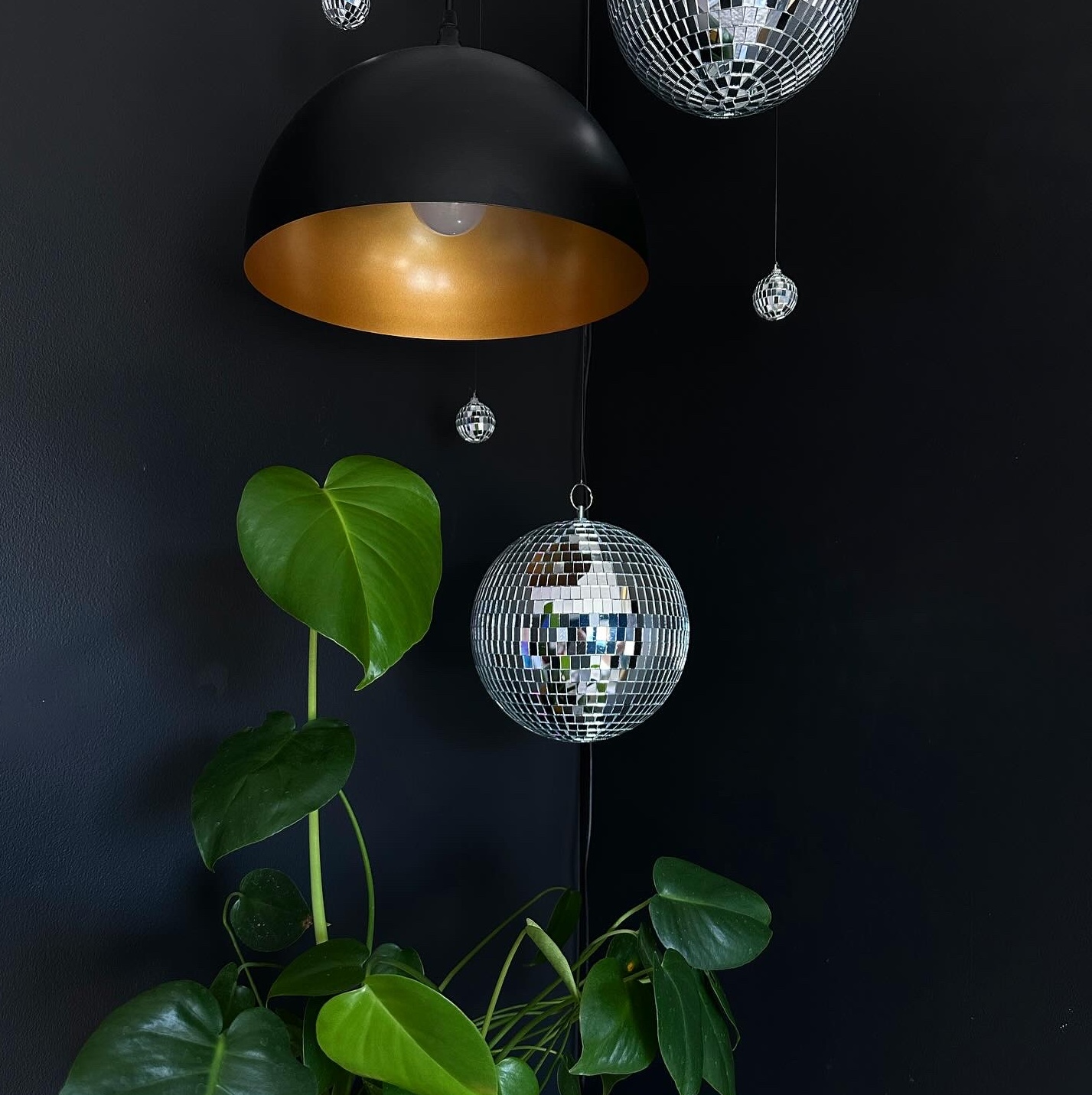 hanging pendant light with hanging disco balls in different sizes with plant under