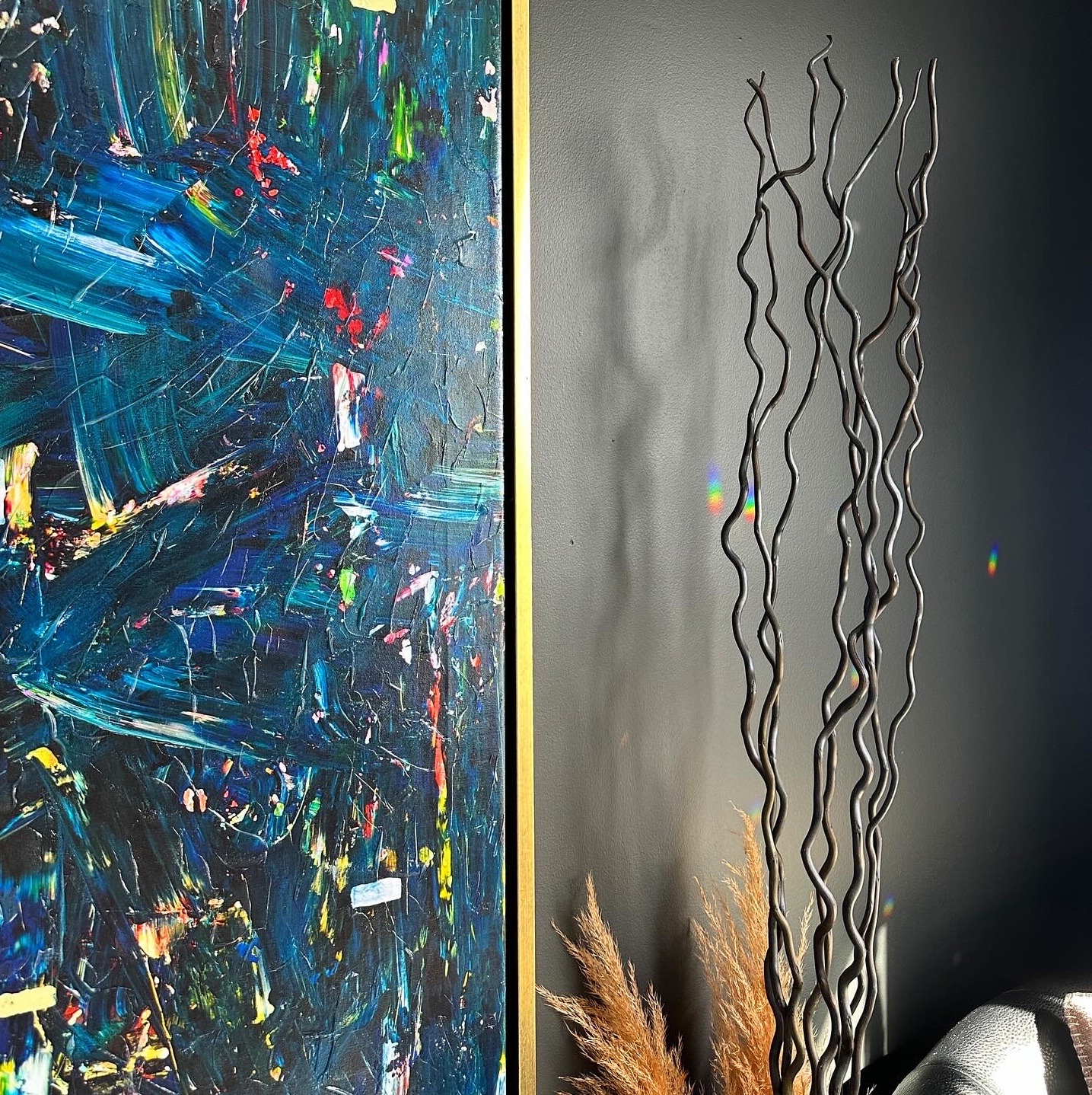 abstract painting on black wall with decorative twigs beside